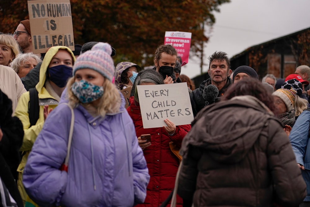 Demonstrators hold placards as they take part to a protest outside the Manston immigration short-term holding facility near Thanet, Kent, England, Sunday, Nov. 6, 2022. (AP)