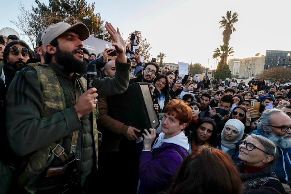 A Syrian fighter, left, gives an address while activists gather at the Umayyad square during a protest to demand a secular state, in Damascus, Syria, Thursday, Dec. 19, 2024 (AP)