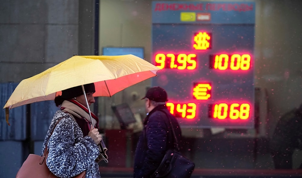 Pedestrians walk in a street near an exchange office sign showing the currency exchange rates of the Russian ruble, U.S. dollar, and euro in Moscow, Russia, Wednesday, Nov. 20, 2024. (AP)