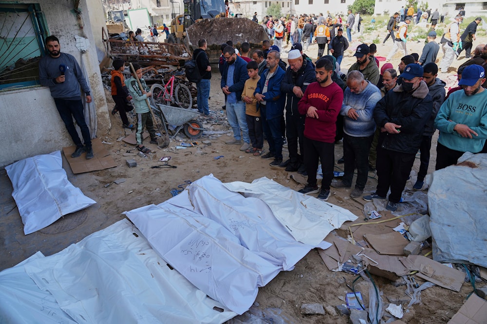 Palestinians pray over the bodies of those killed during the Israel-Hamas war and were buried in a mass grave at Shifa Hospital yard after they exhumed for identification and reburial in Gaza City's official cemeteries, on Thursday, March 13, 2025 (AP)
