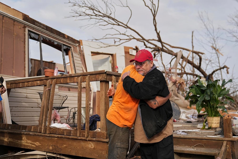 Tim Scott, right, gets a hug from friend Jorden Harris outside Scott's home he was inside when it was destroyed during a severe storm, Wayne County, Mo, Saturday, March 15, 2025 (AP)