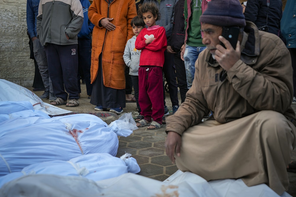 Children watch as the bodies of victims from overnight Israeli army strikes at multiple locations in the central Gaza Strip are laid together for funeral prayers, at Al-Aqsa Martyrs Hospital in Deir al-Balah, Friday, Jan. 3, 2025. (AP)