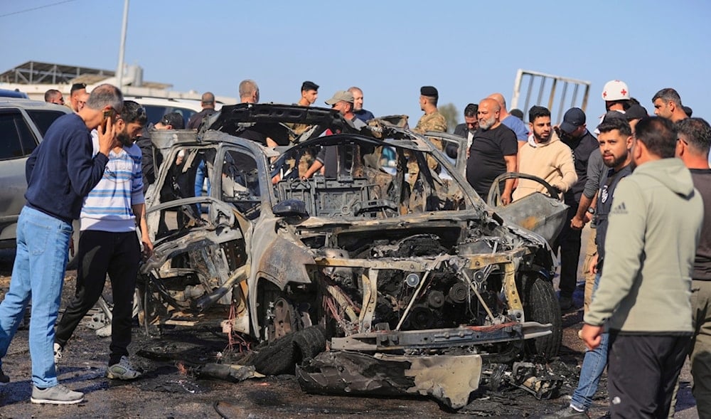 People gather near a charred car that was hit by an Israeli strike, in the southern coastal town of Ghazieh, Lebanon, Friday, April 18, 2025. (AP)