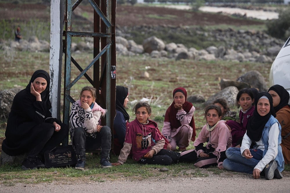 Local residents wait on the side of the road to be evacuated due to fears of Israeli army incursions, on the outskirts of the village of Koayiah, southwestern Syria, Tuesday, March 25, 2025 (AP)