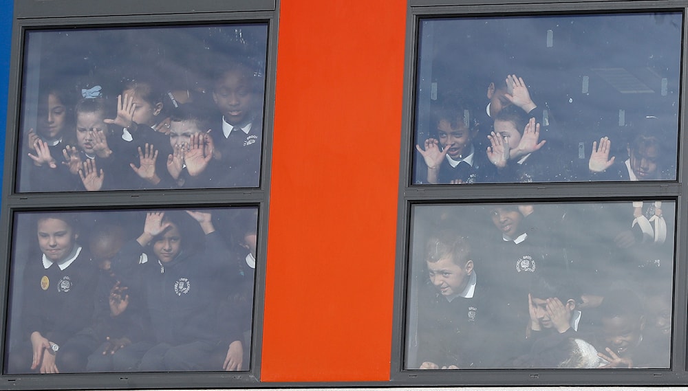 School children look out of windows when Britain's Kate, The Duchess of Cambridge and Prince William leave after attending 'The Big Assembly' by Place2Be hosted at Mitchell Brook Primary School in London, Monday, Feb. 6, 2017.