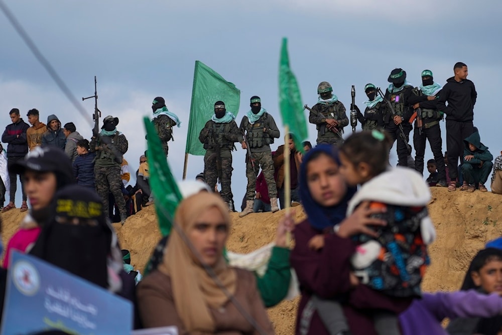 Palestinians watch as Hamas fighters take up a position ahead of handing over four bodies to the Red Cross in Khan Younis, southern Gaza Strip, Thursday, February 20, 2025 (AP)