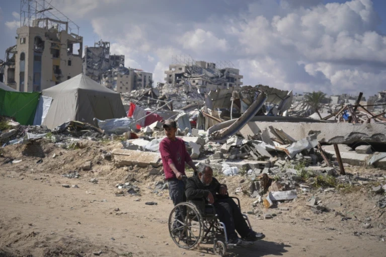 Wasem Attiya pushes his father, Mohamed, 54, in a wheelchair as they head to Shifa hospital in Gaza City for a dialysis session, Monday, April 14, 2025 (AP/Jehad Alshrafi)