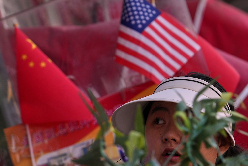 A woman walks past Chinese and United States' national flags on display at a merchandise store in Beijing, Thursday, April 3, 2025. (AP)