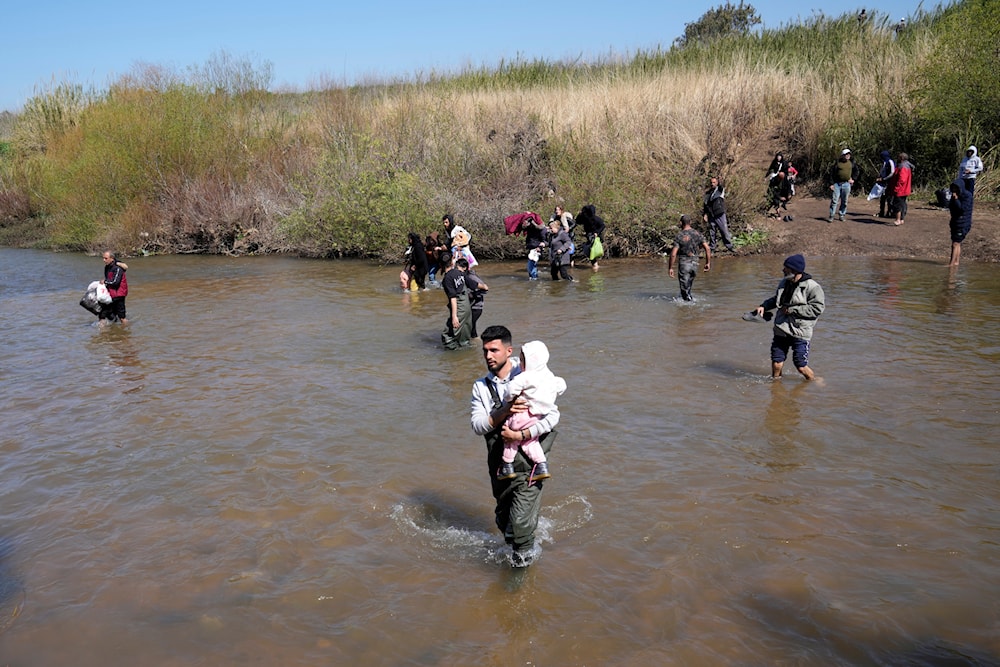 FILE - Syrian Alawite families cross a river marking the border between Syria and northern Lebanon in Heker al-Daher village in Akkar province, Tuesday, March 11, 2025. (AP)