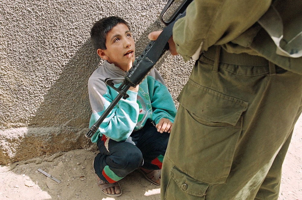 A Palestinian boy is detained by an armed Israeli soldier in the Jabaliya refugee camp in Gaza Strip, March 30, 1994. (AP)