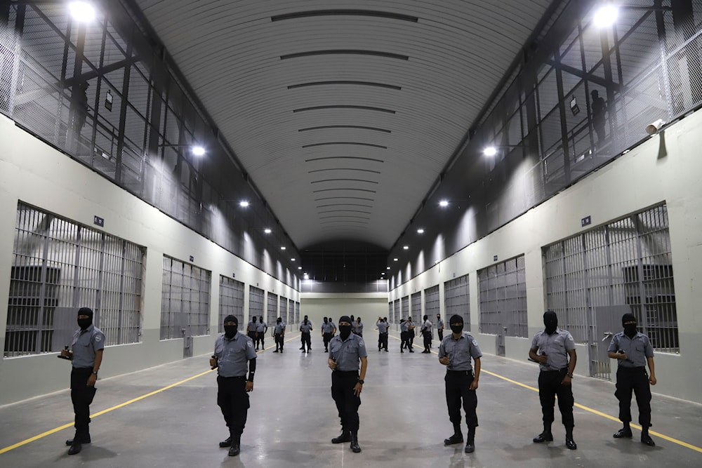 Prison guards stand outside holding cells during a media tour of the Terrorism Confinement Center, or CECOT, in Tecoluca, El Salvador, Feb. 2, 2023. (AP)