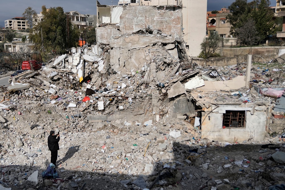 A Lebanese man takes pictures of a destroyed house caused by the Israeli air and ground offensive, in Aita al-Shaab, a Lebanese border village with Israel, south Lebanon, Sunday, Jan. 26, 2025. (AP)