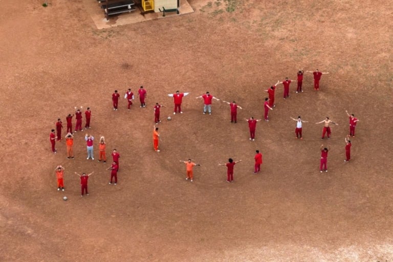 A drone captured the men arranging themselves to spell S.O.S. on the dirt at Bluebonnet detention center, Texas (Picture: Paul Ratje/Reuters)