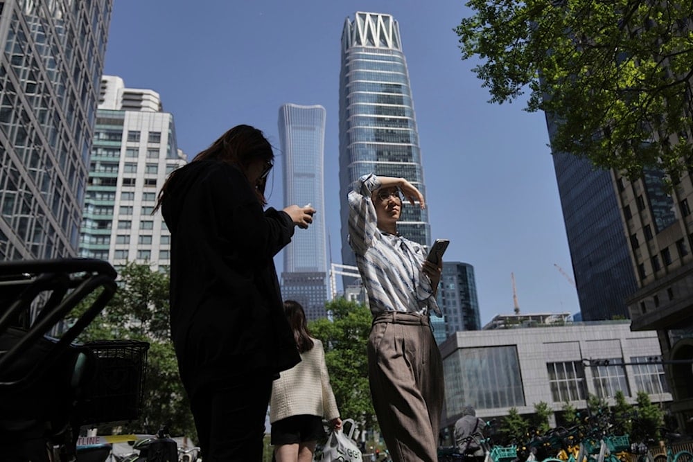 Women walk past office buildings during their lunch break at the Central Business District, in Beijing, Monday, April 28, 2025 (AP)