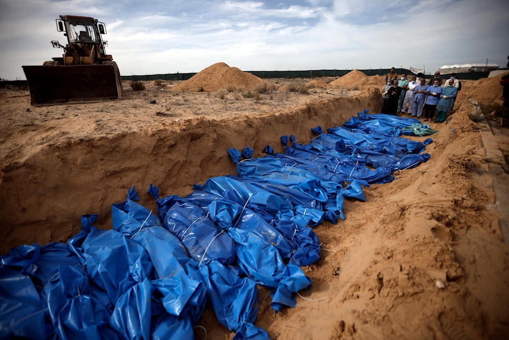 Palestinians pray over bodies of people killed in the Israeli bombardment who were brought from the Shifa hospital before burying them in a mass grave in the town of Khan Younis, southern Gaza Strip, Wednesday, Nov. 22, 2023. (AP )