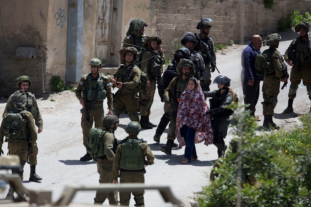 Israeli soldiers arrest a Palestinian woman during an arrest raid, in the village of Yabad near the West Bank city of Jenin, Tuesday, May. 12, 2020. (AP)