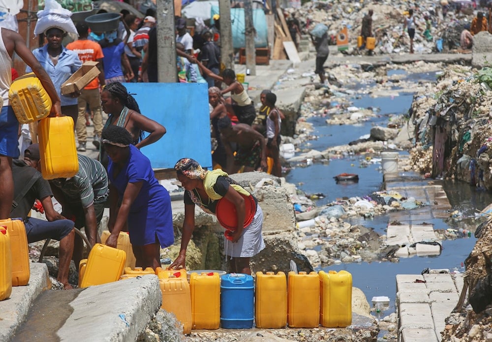 People wait to fill their containers with drinking water from broken underground pipes in Port-au-Prince, Haiti, Friday, May 9, 2025. (AP)