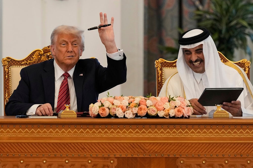 President Donald Trump holds up a pen given by Qatar's Emir Sheikh Tamim bin Hamad Al Thani as they exchange documents during a signing ceremony at the Amiri Diwan in Doha, Qatar, Wednesday, May 14, 2025 (AP)
