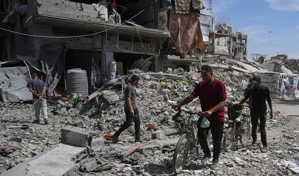 Palestinians walk through rubble along a road beside a clinic destroyed by Israeli airstrikes in Jabalia, in the northern Gaza Strip, on Thursday, May 15, 2025. (AP)