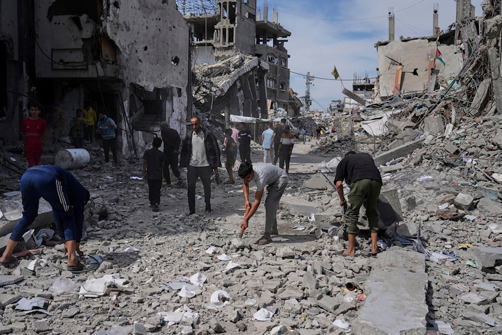 Palestinians clean the rubble along a road beside a clinic destroyed by Israeli airstrikes in Jabalia, in the northern Gaza Strip, on Thursday, May 15, 2025 (AP)