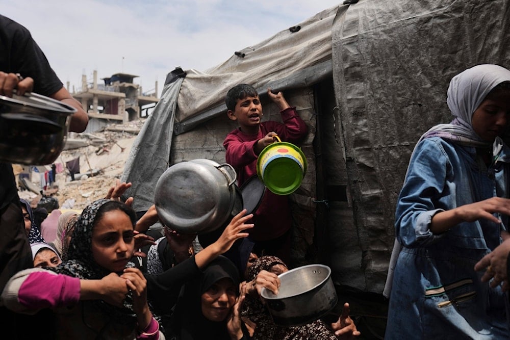 Palestinians struggle to get donated food at a community kitchen in Jabalia, northern Gaza Strip, Thursday, May 15, 2025 (AP)