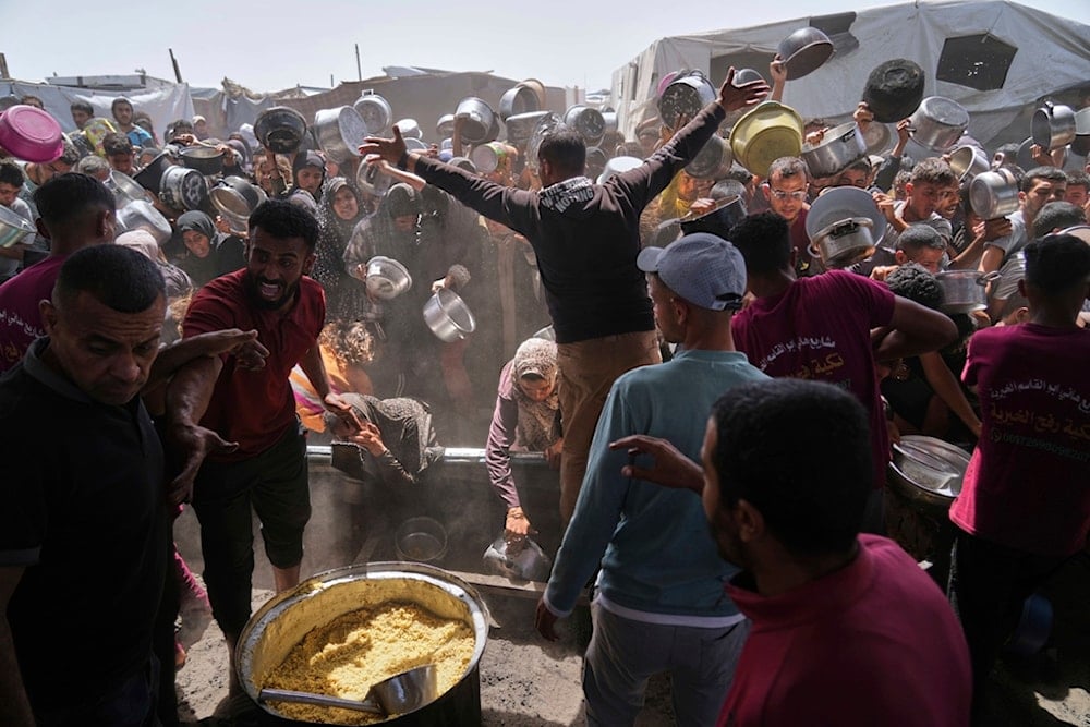 Palestinians struggle to get donated food at a community kitchen in Khan Younis, Gaza Strip, Friday, May 16, 2025 (AP)