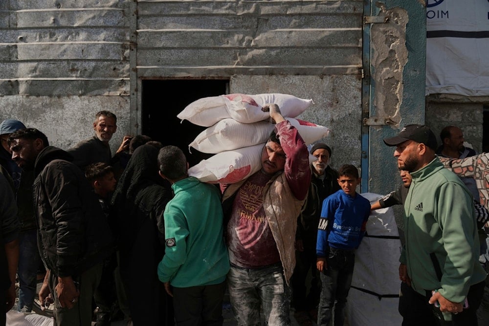 Palestinians receive bags of flour and other humanitarian aid distributed by UNRWA, the UN agency helping Palestinian refugees in Jabaliya, Gaza Strip, on Tuesday, March 25, 2025 (AP)