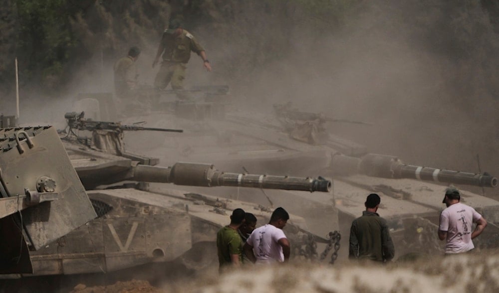 Israeli occupation troops work on tanks at a staging area near the border with the Gaza Strip, in southern Palestine, Sunday, May 18, 2025. (AP)