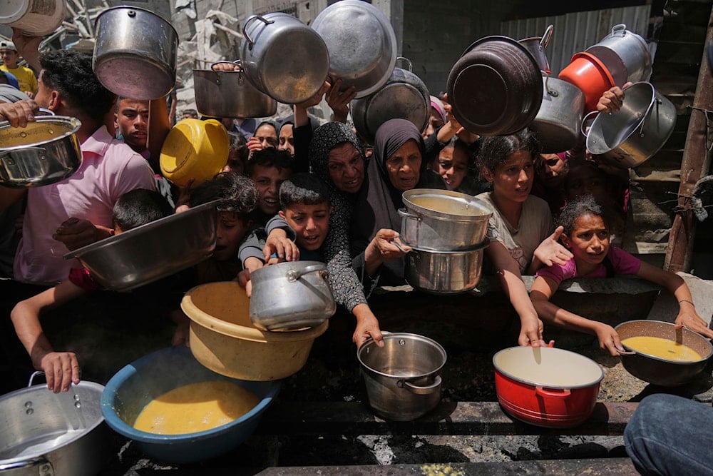 Palestinians struggle to get donated food at a community kitchen in Jabalia, northern Gaza Strip, Monday, May 19, 2025 (AP)