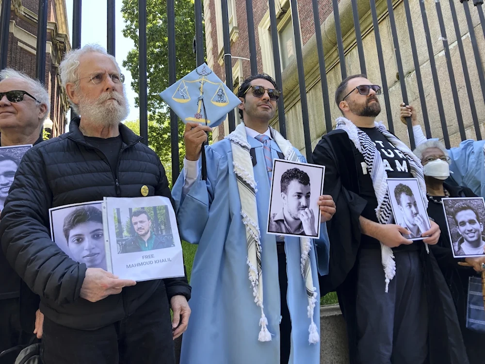 Mohsen Mahdawi, center, holds a photo of Mahmoud Khalil while posing for a photo with demonstrators outside the gates of Columbia University after graduating May 19, 2025 in New York (AP/Jake Offenhartz)