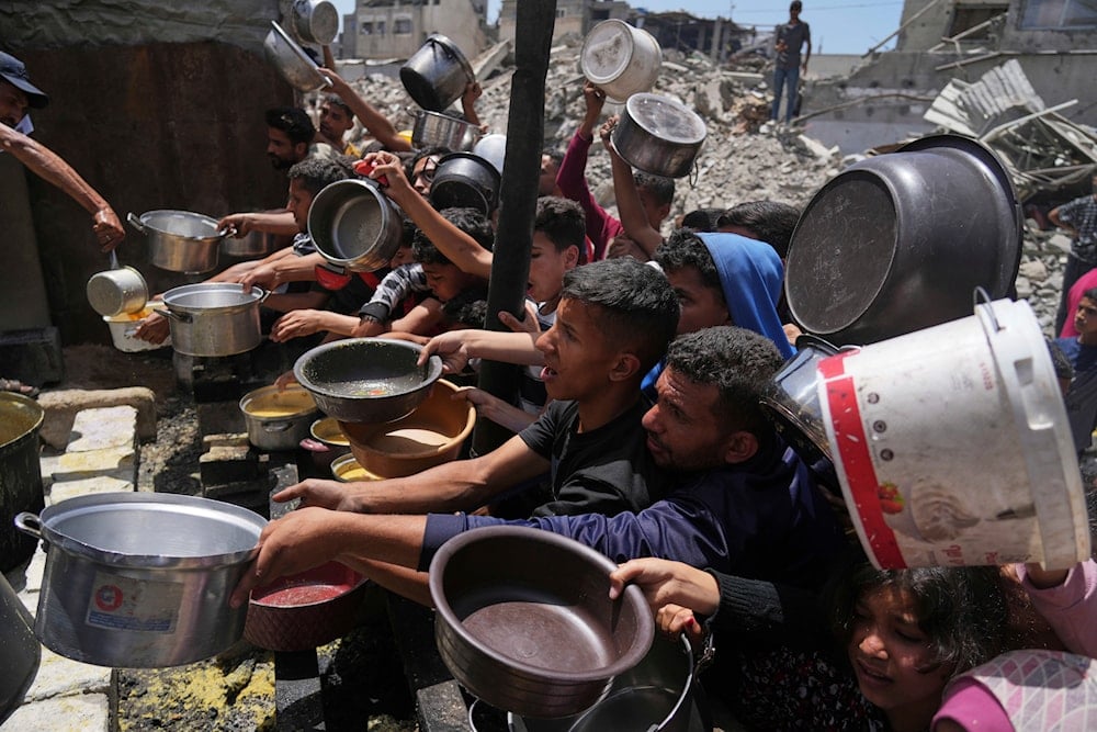 Palestinians struggle to get donated food at a community kitchen in Jabalia, northern Gaza Strip, Monday, May 19, 2025 (AP)