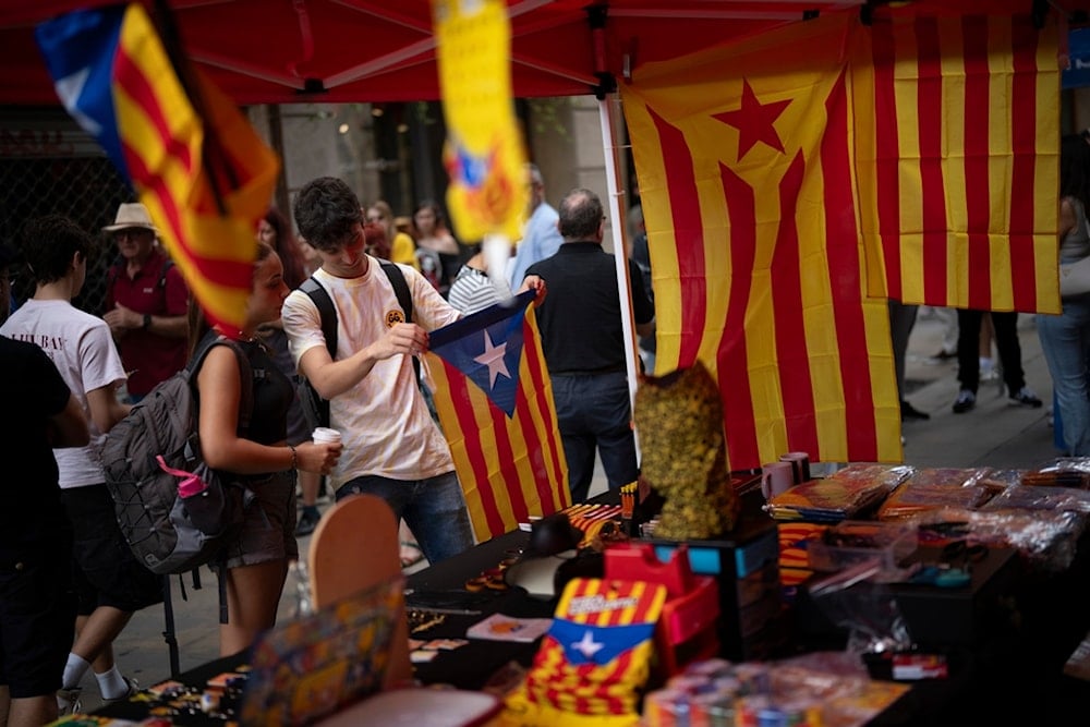 Customers buy an independence flag during the Catalan National Day, during the Catalan National Day, which marks the fall of the Catalan capital to Spanish forces in 1714, in Barcelona, Spain, Wednesday, September 11, 2024 (AP)