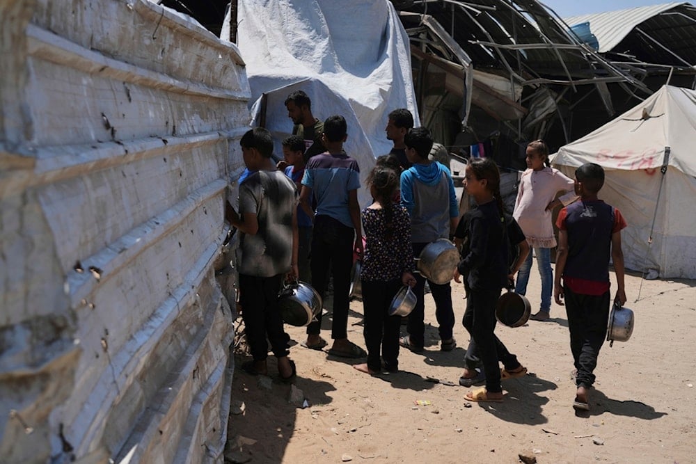 Displaced Palestinians line up to receive donated meals from a community kitchen at a tent camp in Gaza City on Wednesday, May 21, 2025. (AP Photo/Jehad Alshrafi)