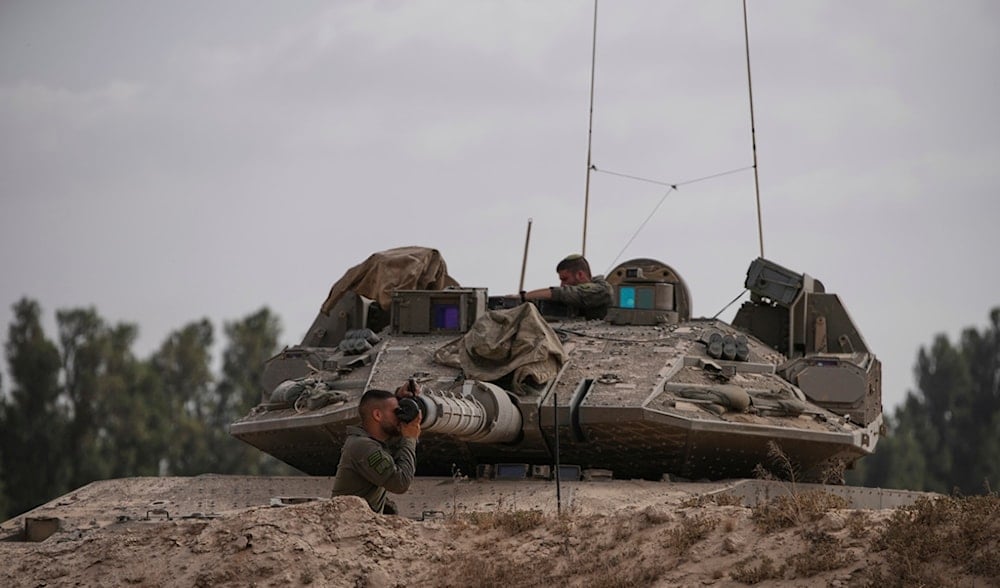 Israeli soldiers work on a tank near the border with the Gaza Strip, in southern occupied Palestine, Monday, May 19, 2025. (AP)
