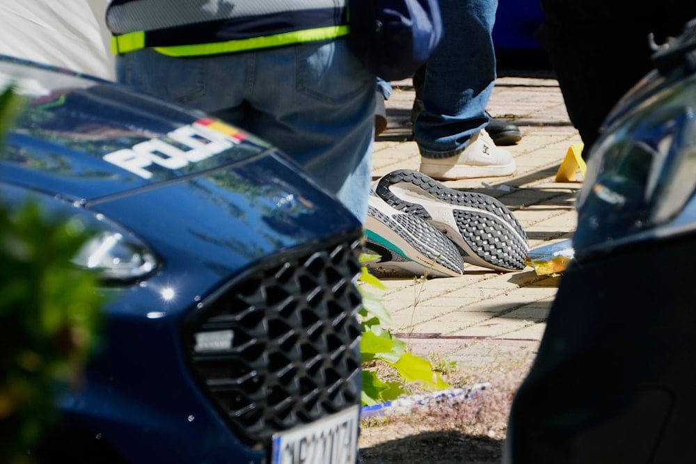 Members of the judicial police work next to the body of Andriy Portnov, an adviser to former Ukrainian president Viktor Yanukovych, who was shot dead on Wednesday outside a school in Madrid, Spain, Wednesday, May 21, 2025 (AP)