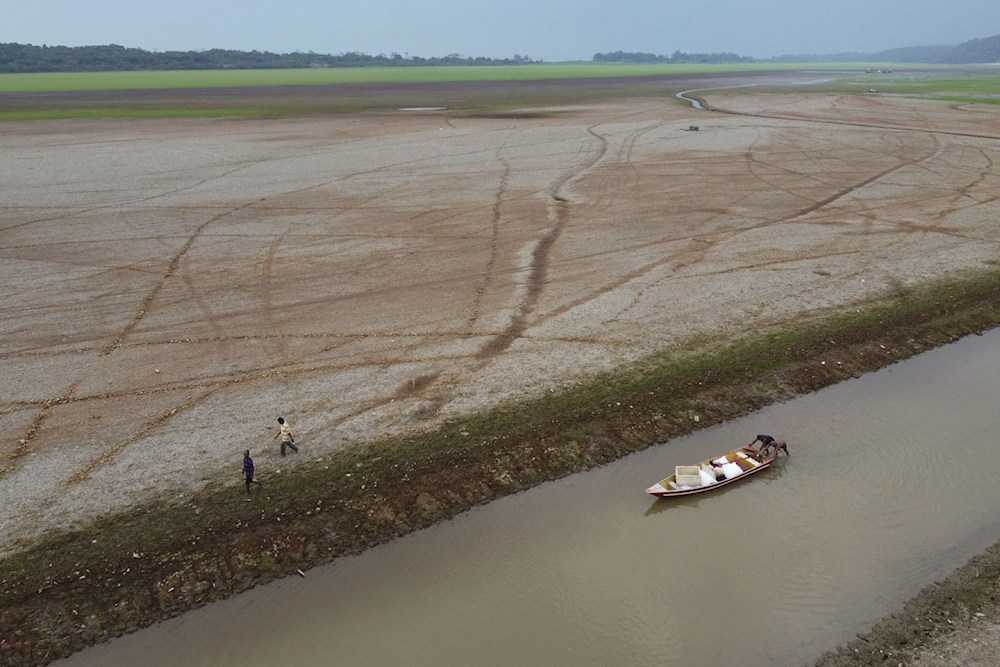 Fisherman push a boat in the Aleixo Lake amid a drought in Manaus, Amazonas state, Brazil, September 24, 2024 (AP/Edmar Barros)