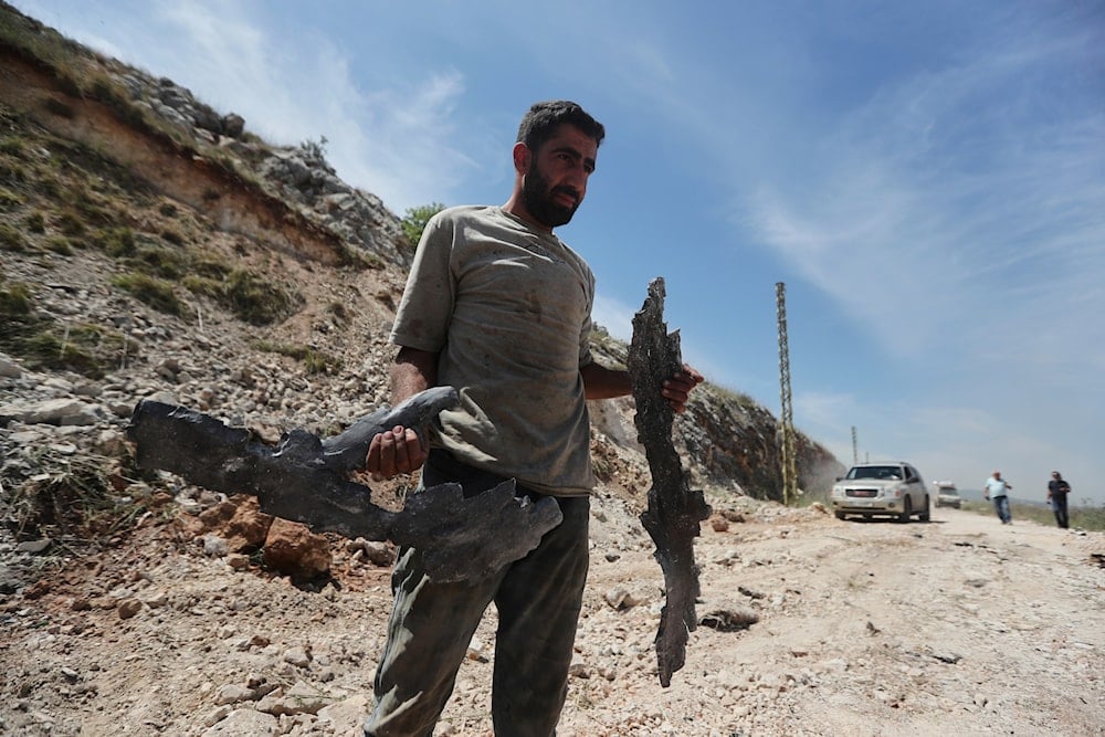 A man carries parts of an Israeli missile following airstrikes that targeted hilltops near Nabatieh town, south Lebanon, Thursday, May 8, 2025 (AP)