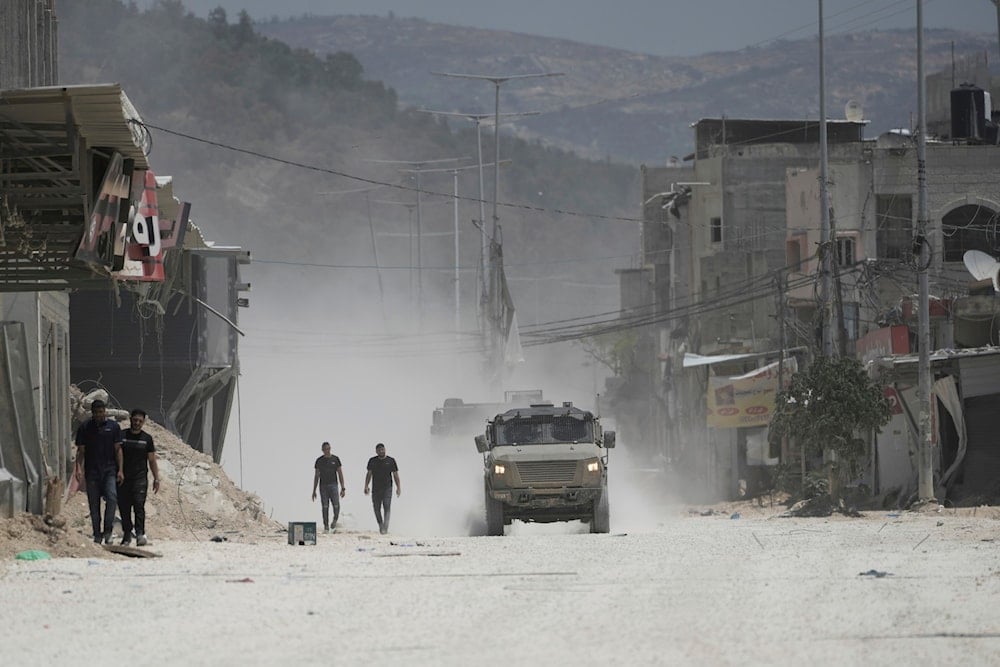 Residents of the West Bank urban refugee camp of Nur Shams walk beside Israeli Army vehicles as people evacuate their homes as the Israeli security forces are preparing to carry out home demolitions in the area, on May 7, 2025. (AP Photo/Majdi Mohammed)