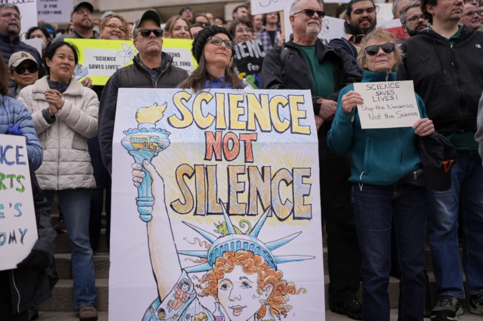 Jennifer Berry, center, wears a sign during a Stand up for Science rally Friday, March 7, 2025, in Nashville, Tenn. (AP/George Walker IV)