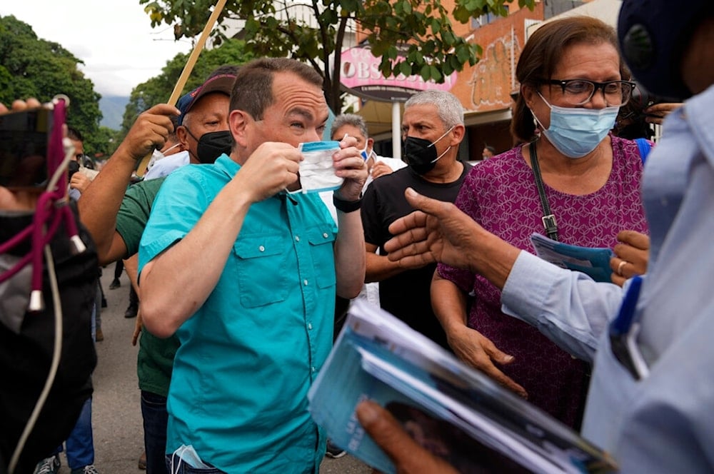 Tomas Guanipa, left, Democratic Unity Table (MUD) mayoral candidate for the Libertador municipality, puts on a face mask as he arrives to greet supporters on the first day of the 2021 campaign, in Caracas, Venezuela, Thursday, Oct. 28, 2021 (AP)