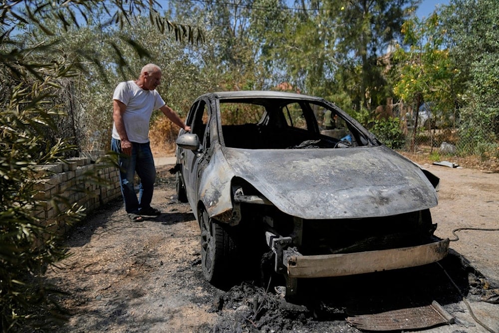 Palestinian landlord Akram Sabra, 60, stands next to a vehicle burnt under attack by Israeli settlers overnight, in the West Bank village of Bruqin, near Salfit Friday, May 23, 2025. (AP Photo/Nasser Nasser)