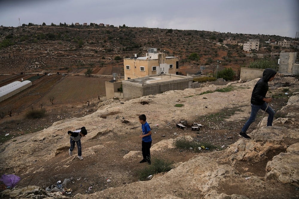 Palestinian boys scramble up a hill in a tense area near several unauthorized Israeli outposts on the edge of the Palestinian village of Qaryout in the northern West Bank, Sunday, Nov. 12, 2023. (AP)