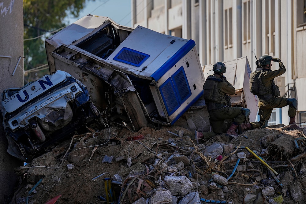 Israeli occupation forces take position next to crumpled-up U.N. vehicles perched precariously atop building debris in UNRWA compound, where the military destroyed in Gaza, Thursday, Feb. 8, 2024. (AP)