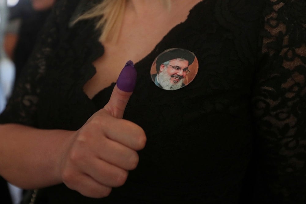 A woman displaying a portrait of martyred Hezbollah leader Hassan Nasrallah, shows her ink-stained thumb after casting her vote at a polling station during municipal elections in the town of Nabatieh, south Lebanon, Saturday, May 24, 2025 (AP)