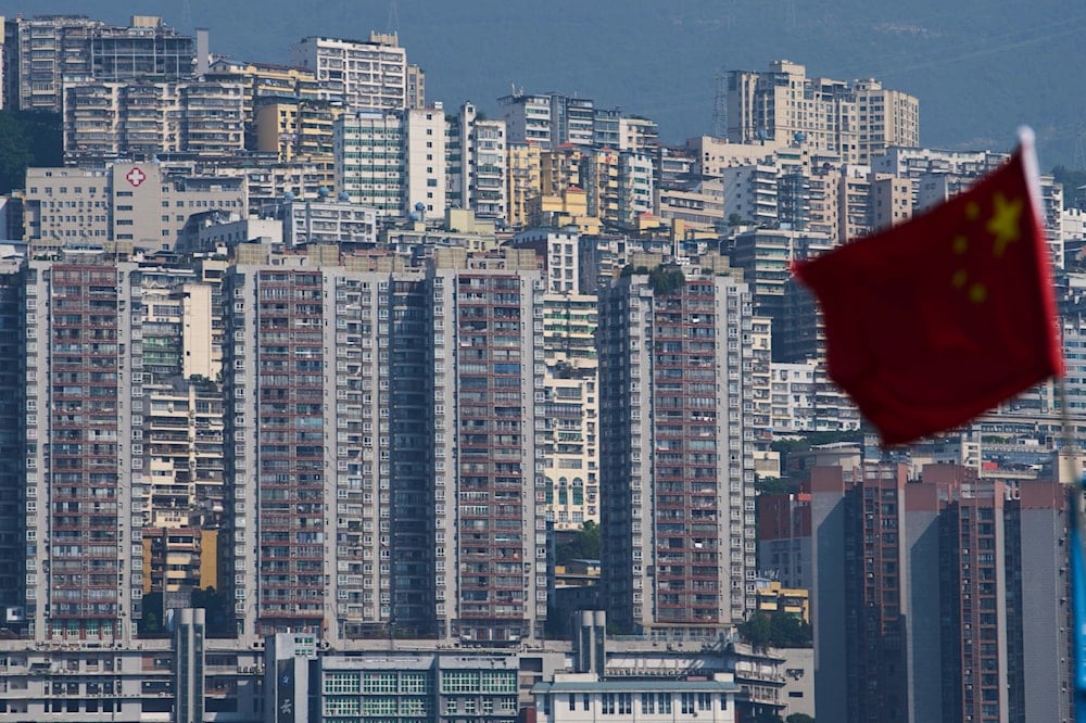 A Chinese national flag flutters against the high-rise residential buildings in Wushan county, in southwest China's Chongqing Municipality, Wednesday, May 21, 2025 (AP)