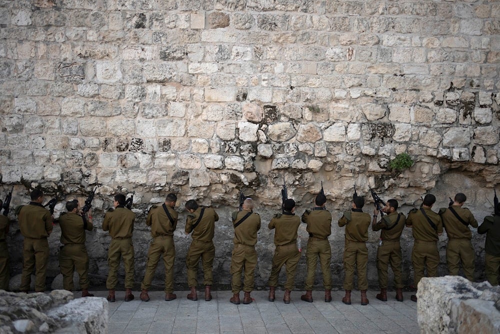 Israeli Occupation Forces paratroopers clear ammunition from their weapons before Al-Quds' Old City, Wednesday, Jan. 8, 2025 (AP)