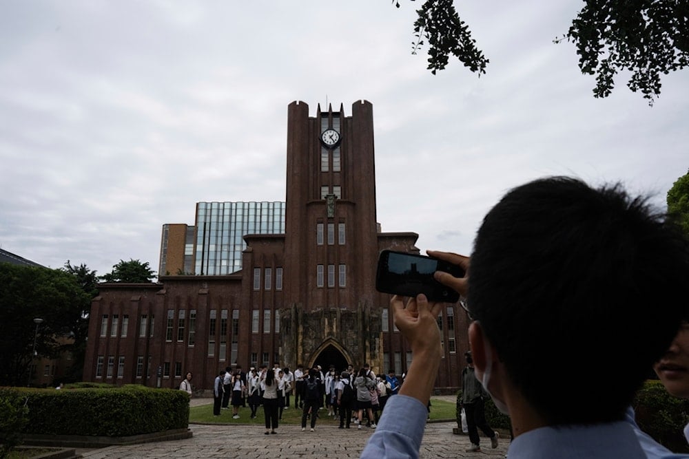 Visitors take photographs of the Yasuda auditorium at the University of Tokyo in Tokyo, Tuesday, May 27, 2025. (AP Photo/Louise Delmotte)