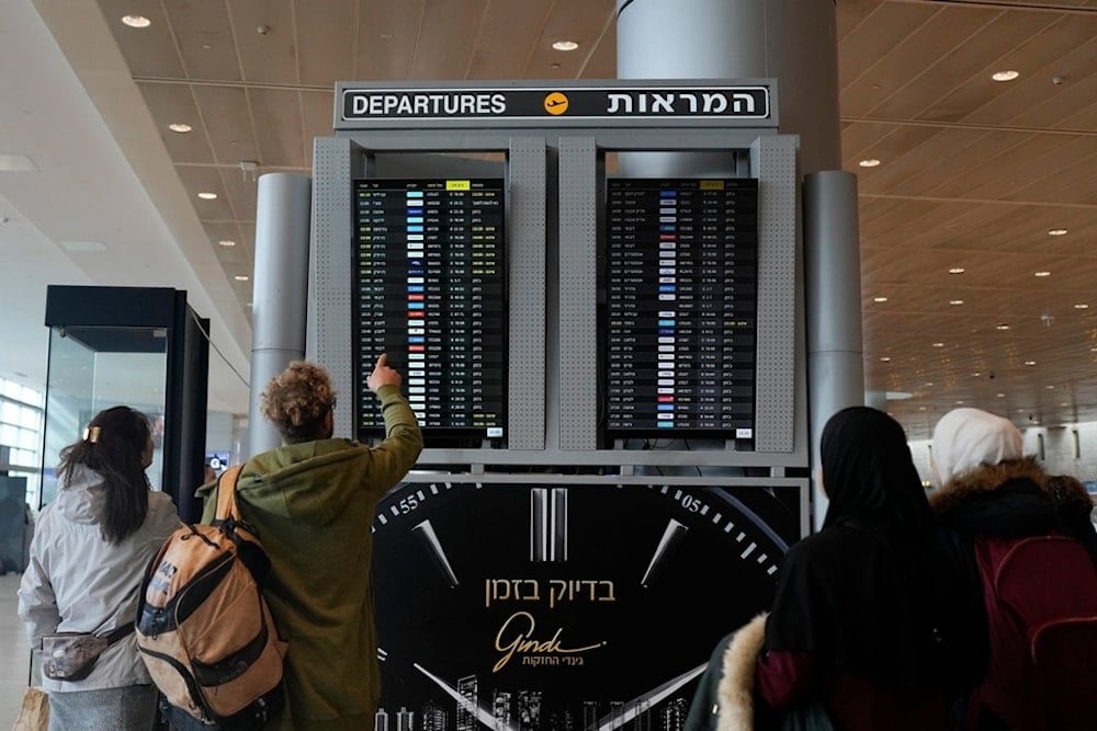 Travelers check departing flights at Ben Gurion International Airport near Tel Aviv, occupied Palestine, Tuesday, December 31, 2024 (AP)