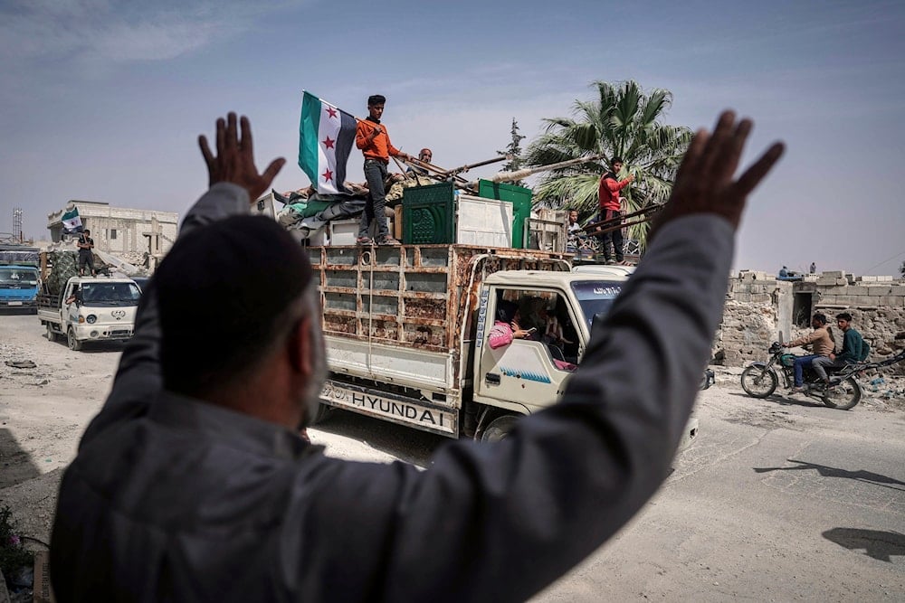 A man greets trucks carrying displaced families as they return to their village after more than five years in the Atmeh camps near the Syrian-Turkish border, in Kafr Sijna, south of Idlib, Syria, Sunday, May 18, 2025 (AP)