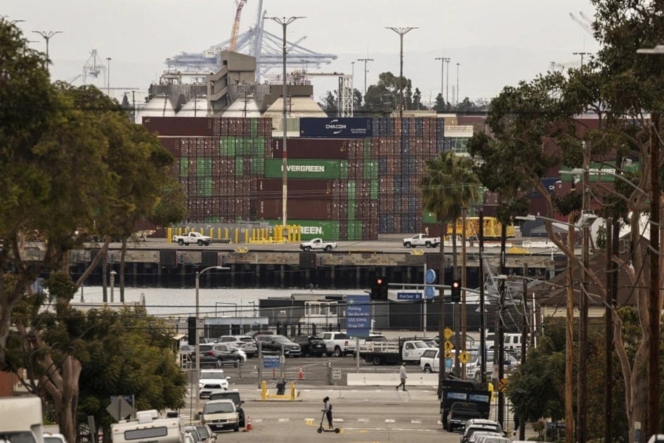 A person on a scooter crosses a street in a residential area located right next to the Port of Los Angeles, Tuesday, March 11, 2025, in San Pedro, California (AP Photo/Etienne Laurent)